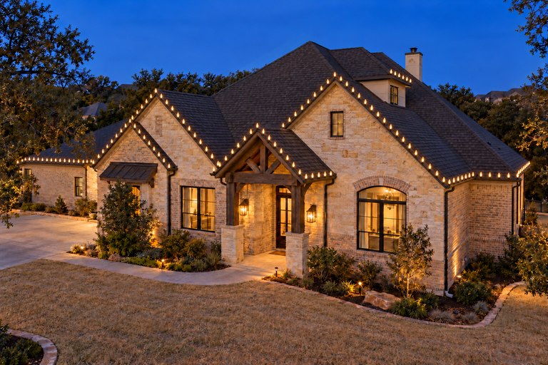 Lighting inspiration: an elevated front-corner view of a North Texas stone-and-brick home with Christmas lights along its street-facing rooflines.
